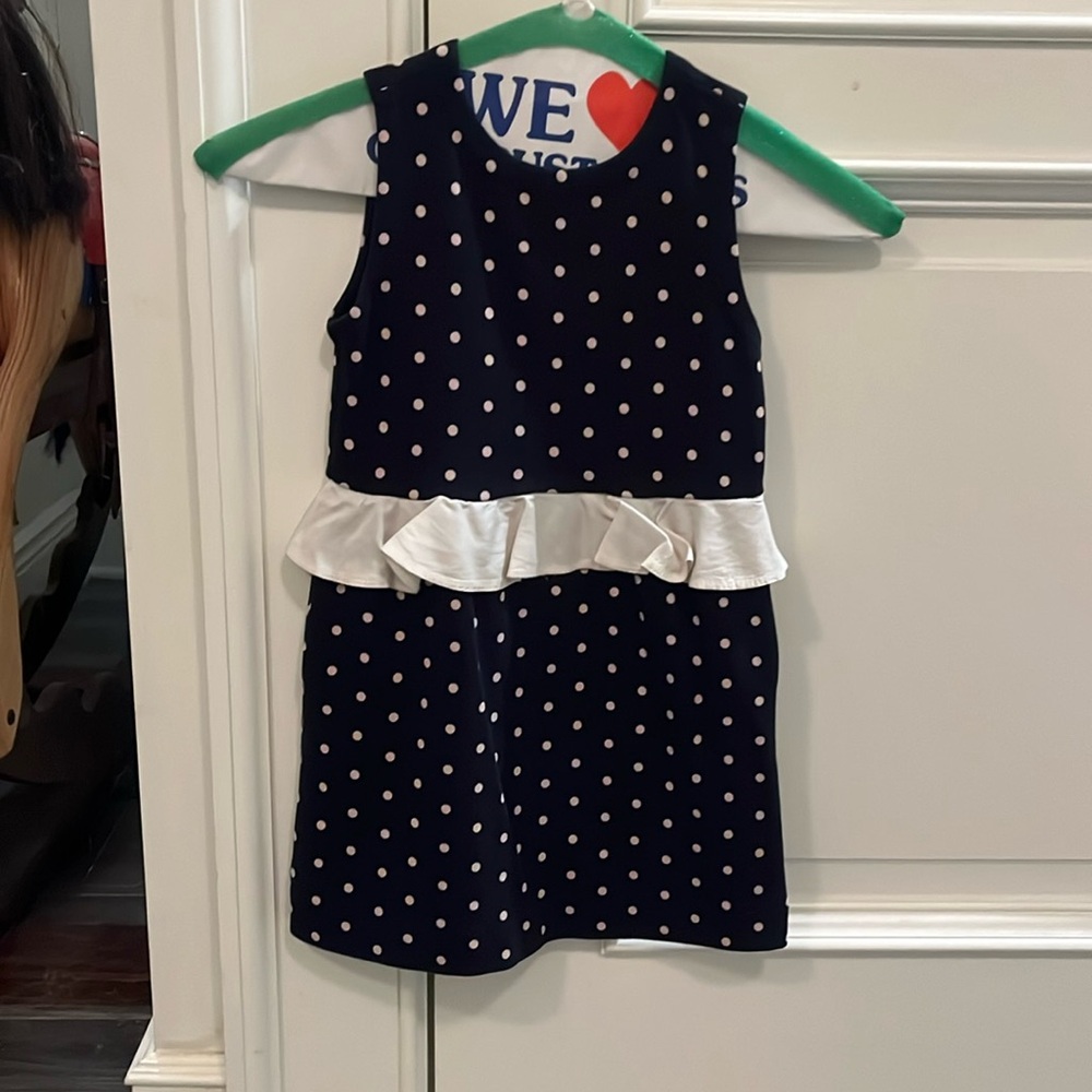 Navy dress with white polka dots and a white ruffle around the waist